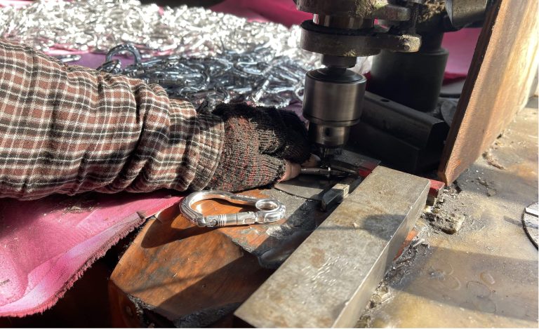 alt="Step 7: riveting the spring gate to ensure a secure and durable carabiner"
